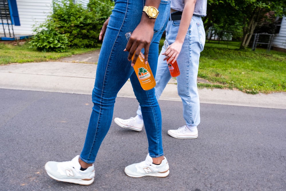 2 person holding orange and blue plastic bottle