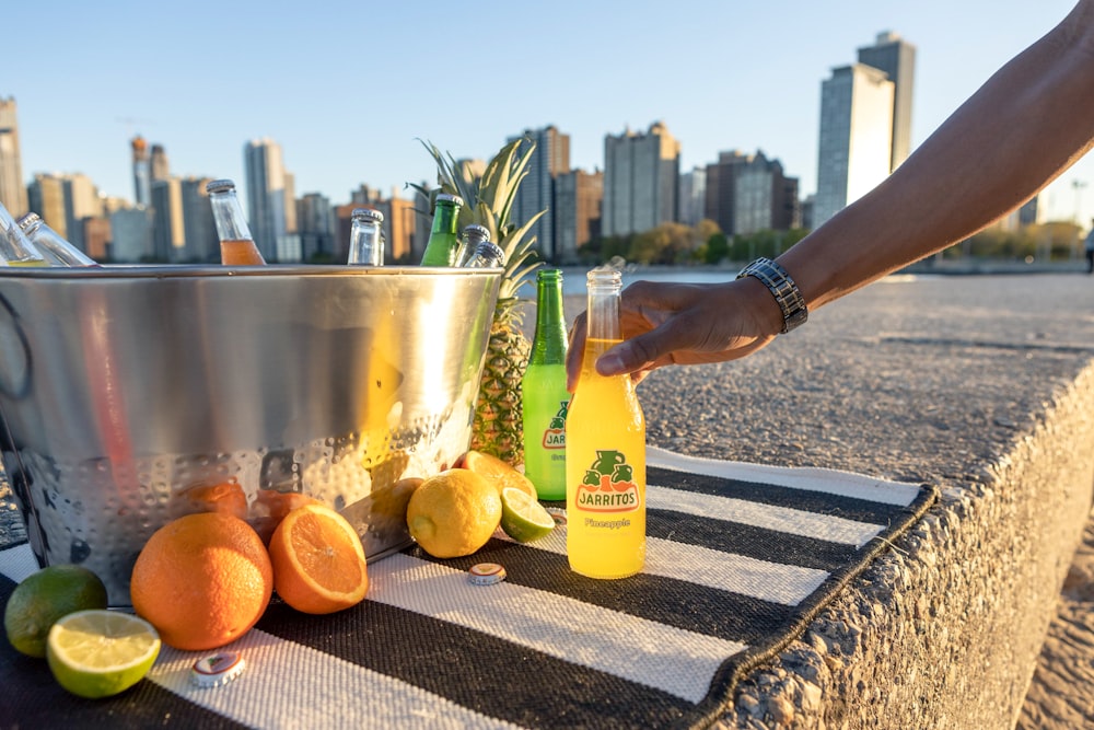 personne versant un liquide jaune sur un verre à boire transparent