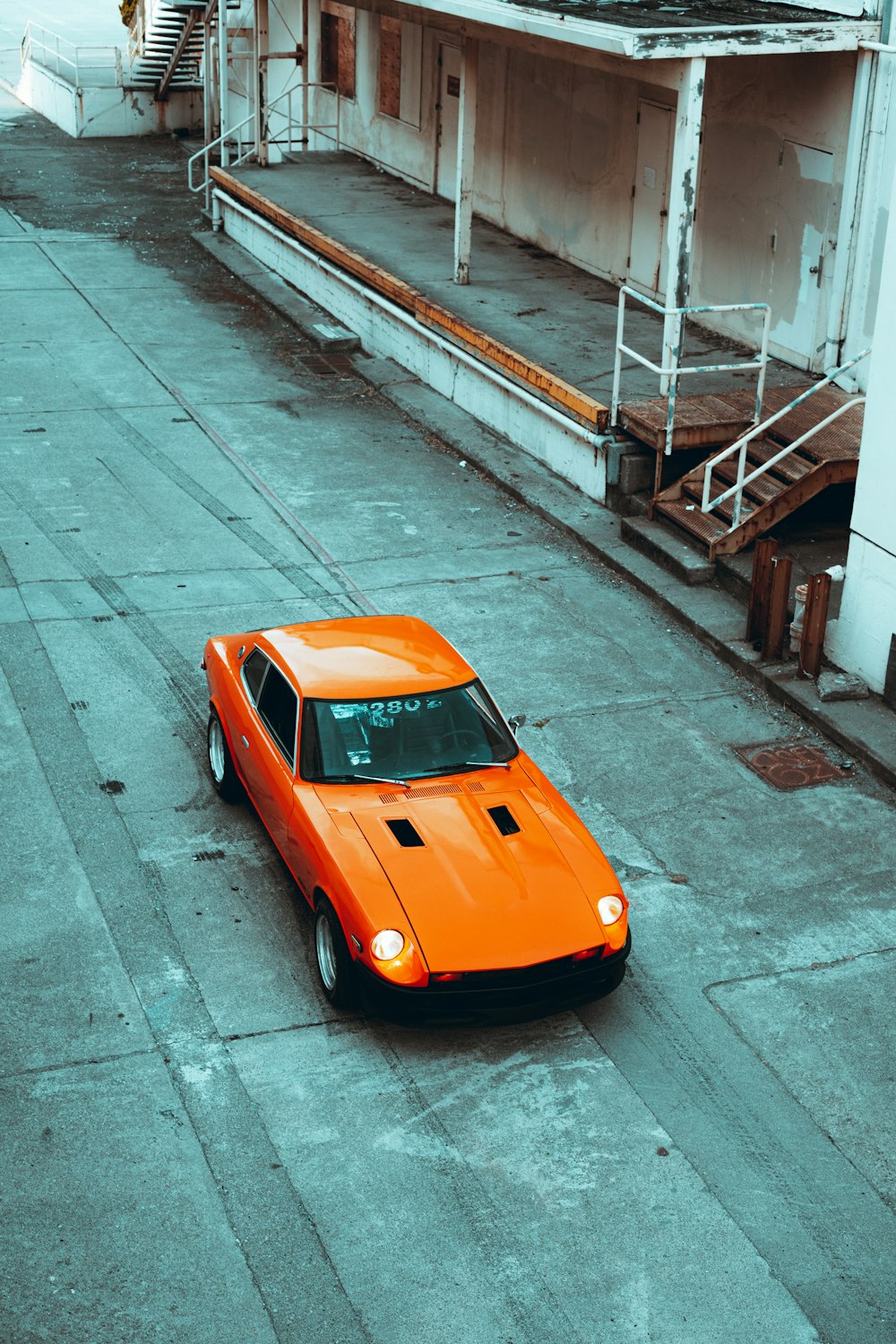 orange car parked on sidewalk during daytime