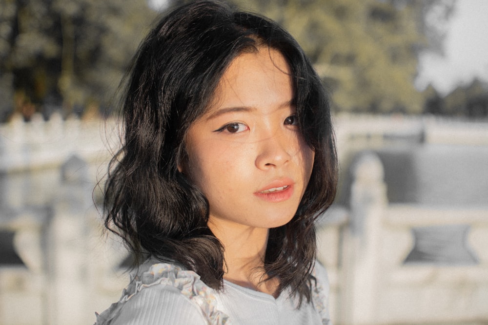 girl in white shirt standing near white fence during daytime