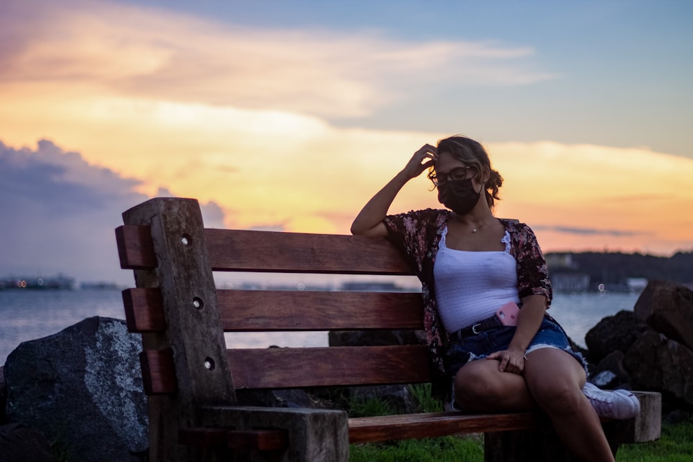 woman in white tank top sitting on brown wooden bench during daytime