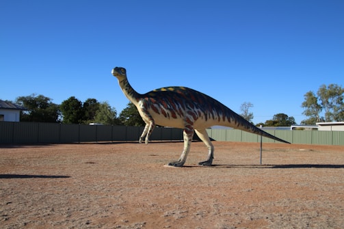 A roaring T-Rex standing against a cloudy prehistoric sky with distant mountains.