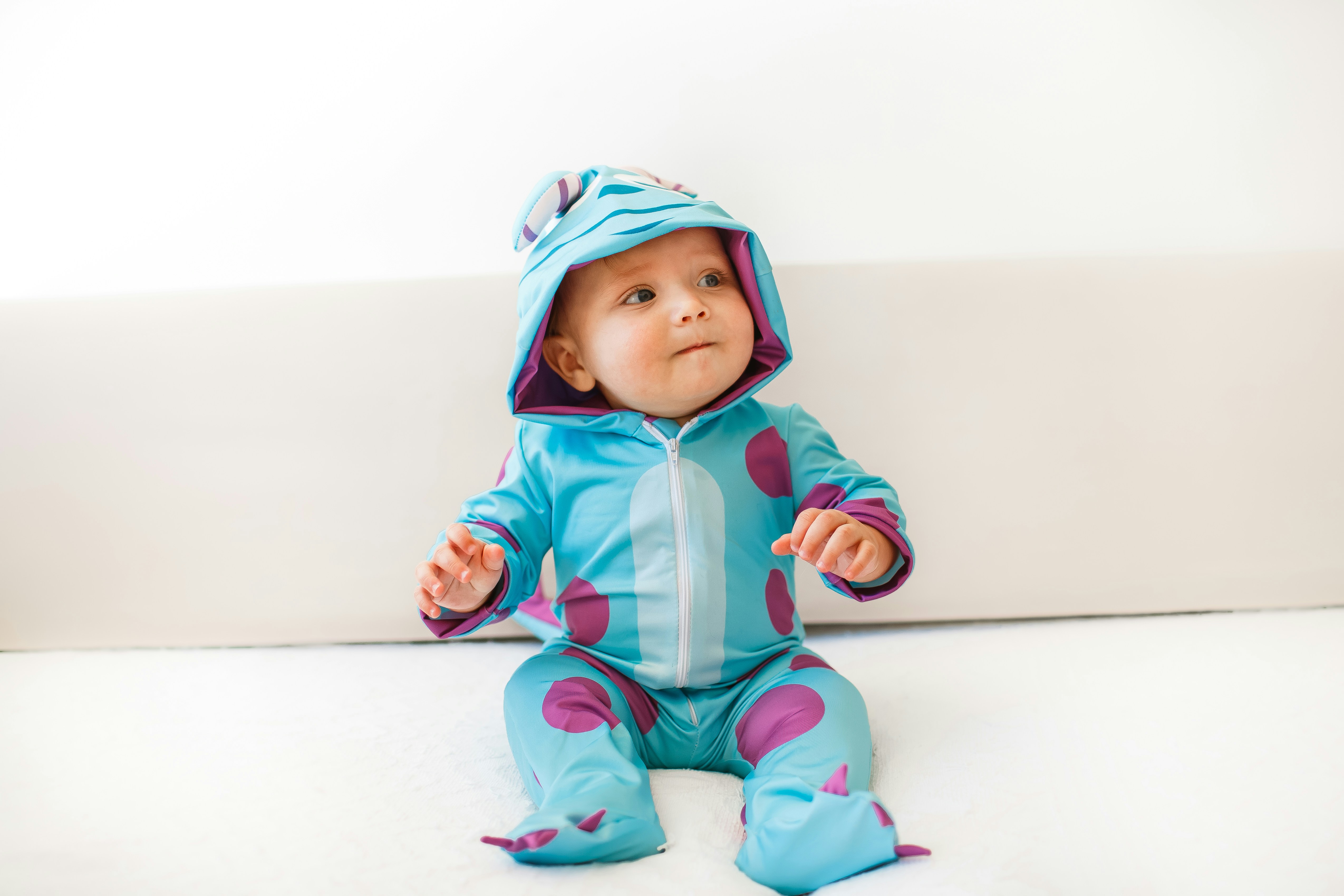 baby in pink hoodie and pants lying on white floor