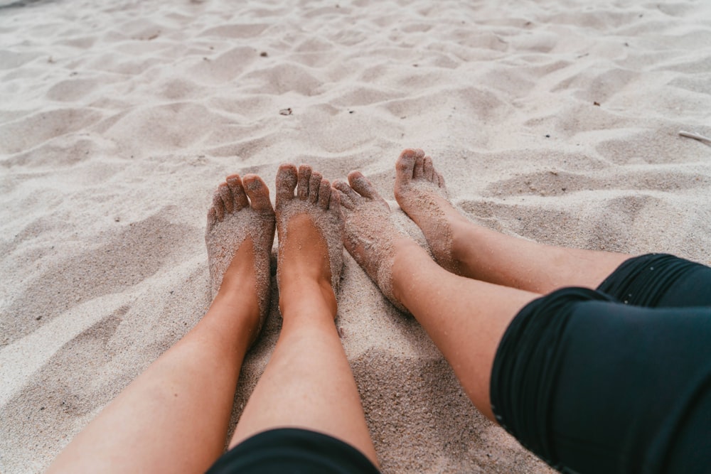 person in black shorts sitting on sand during daytime