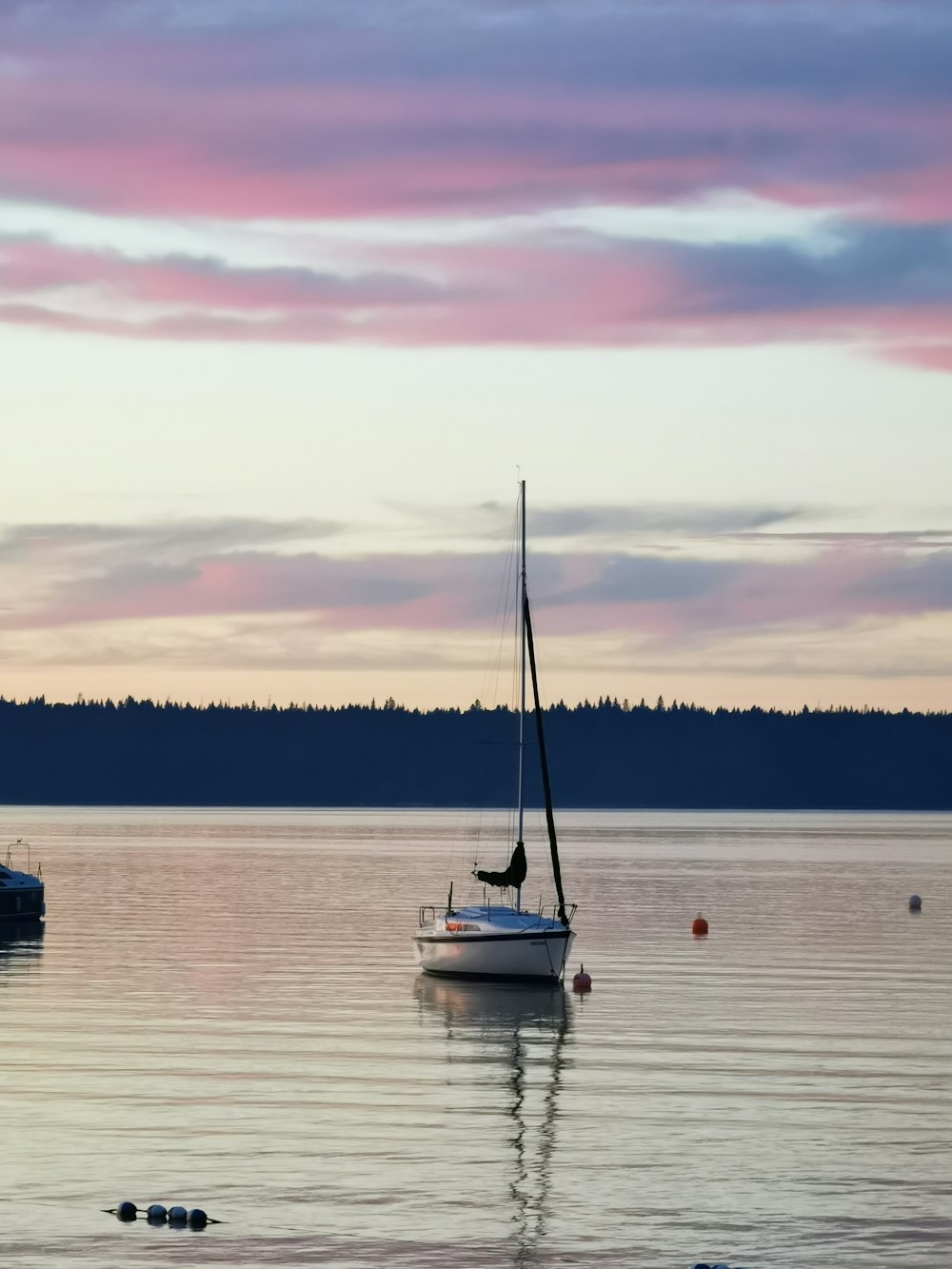 white sail boat on body of water during sunset