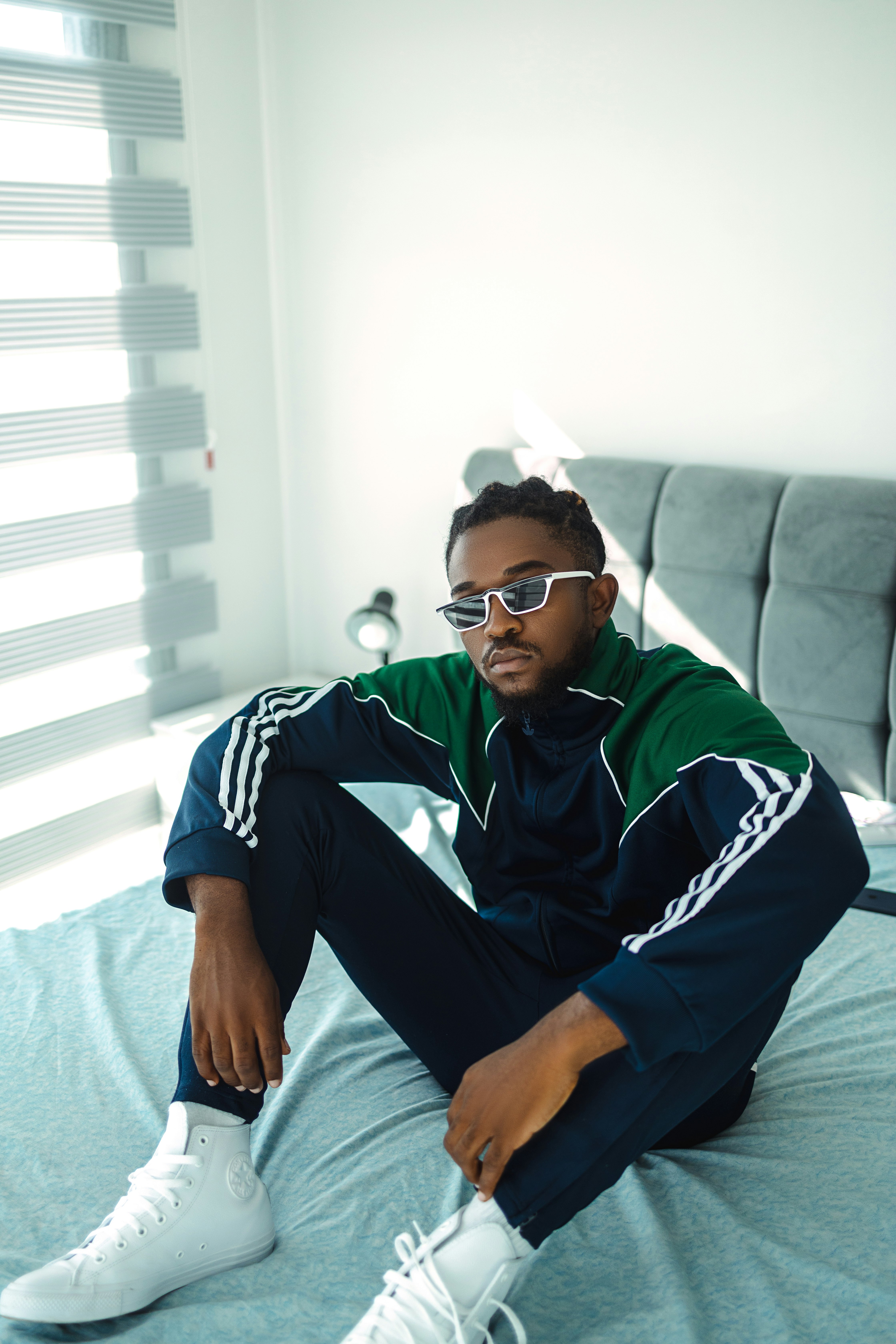 man in blue and white adidas jersey shirt wearing black sunglasses sitting on white couch