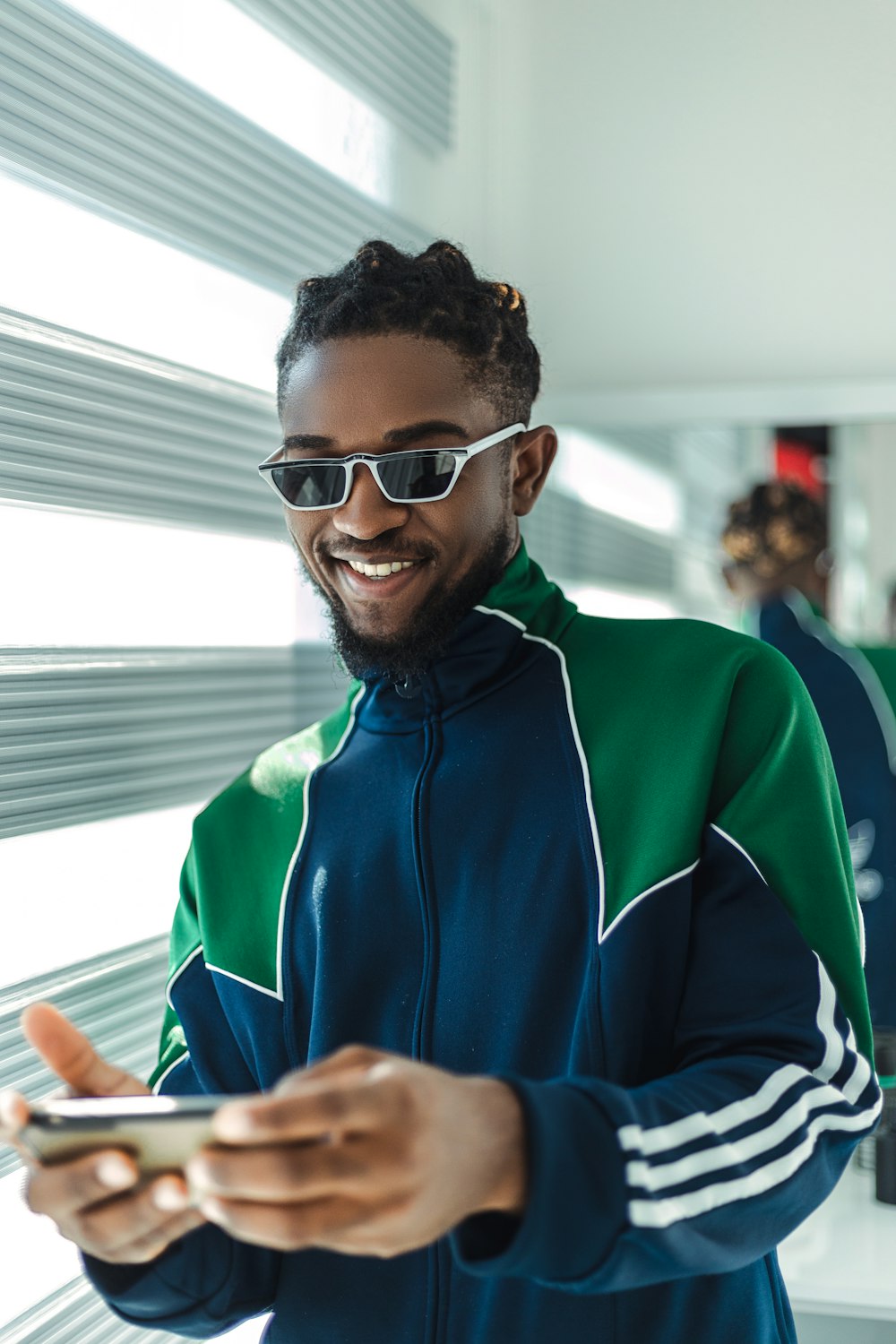 man in blue and green zip up jacket wearing black framed eyeglasses