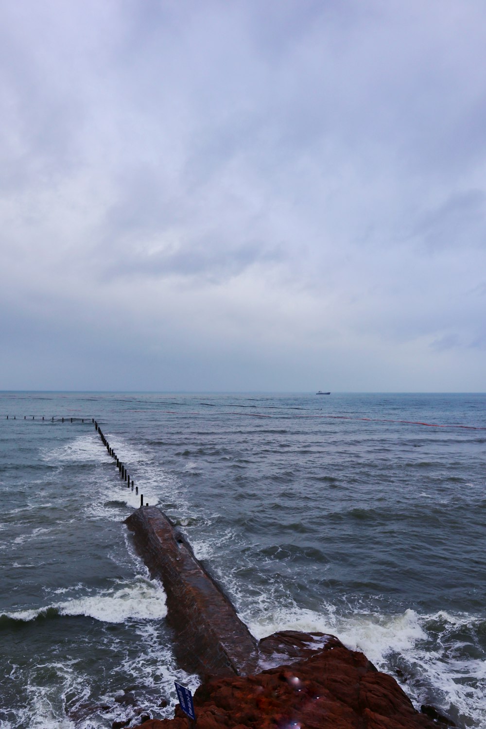 brown wooden log on sea under white clouds during daytime