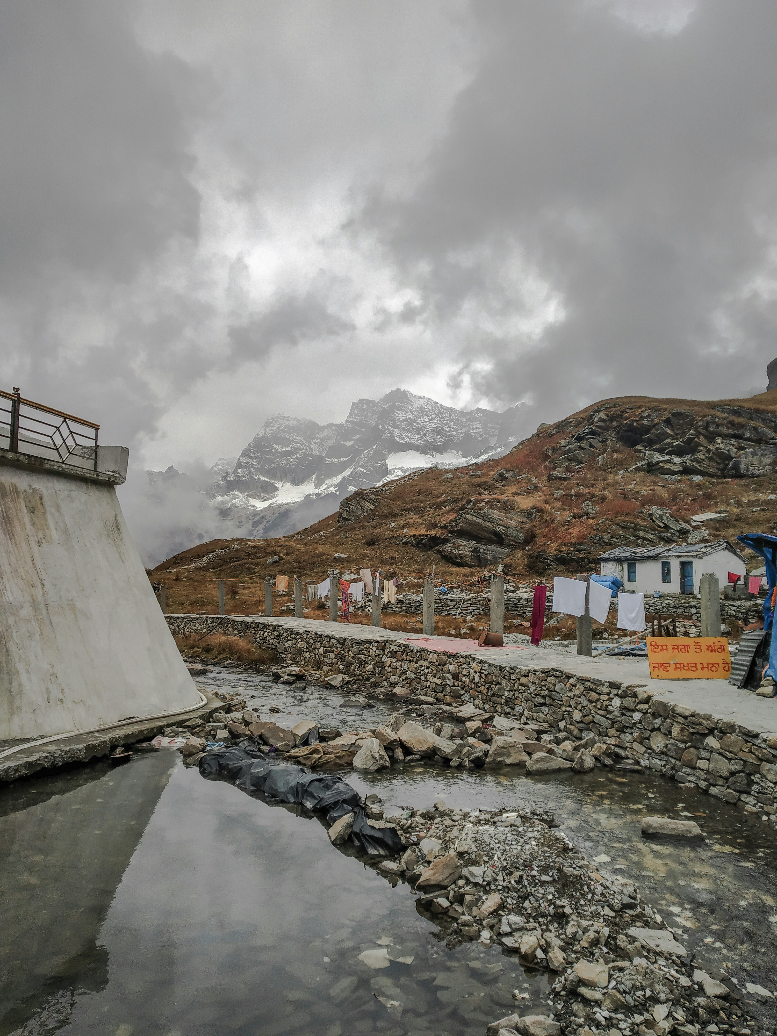 white and brown concrete building near brown and white mountains under white clouds during daytime