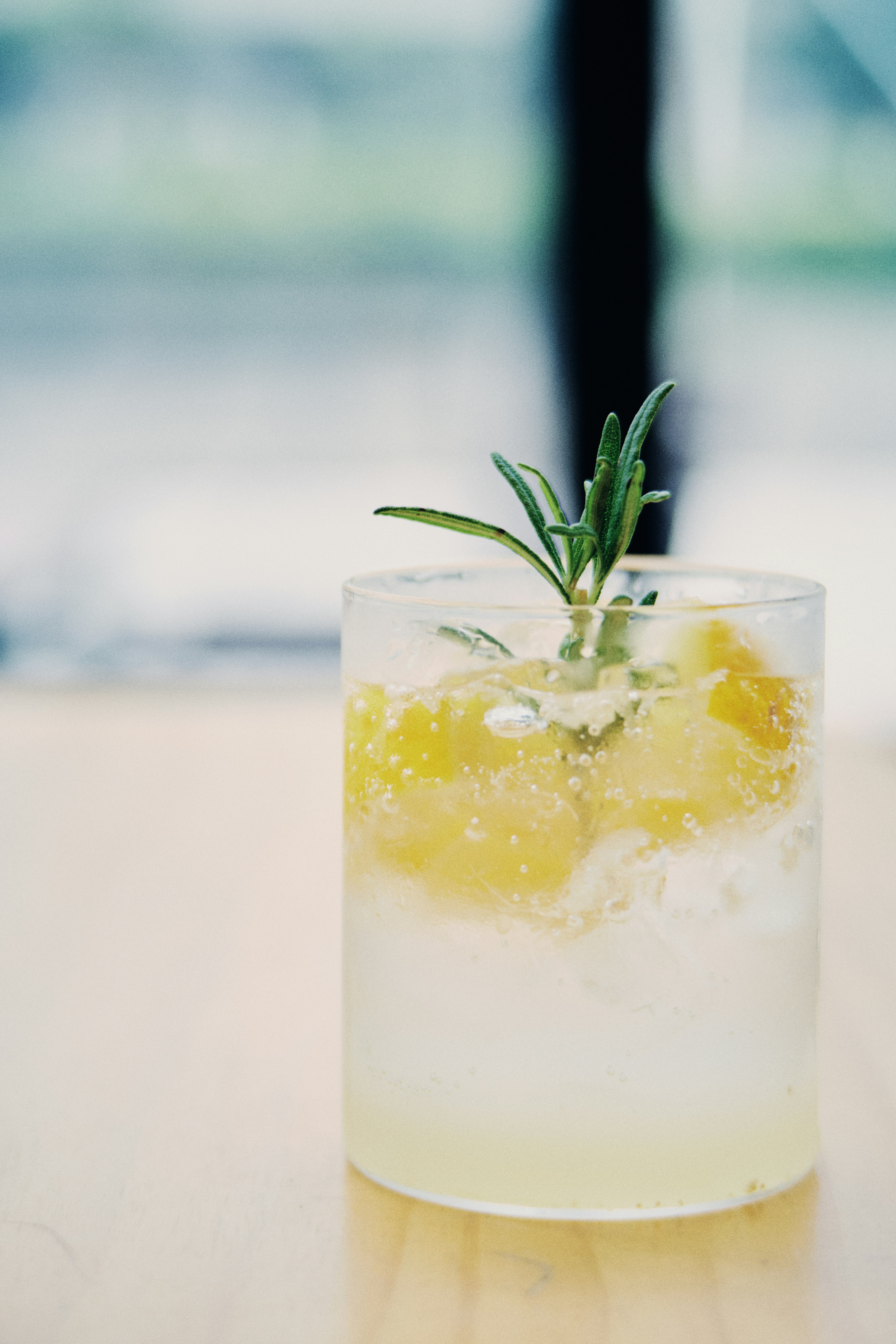 clear drinking glass with yellow liquid and green leaf