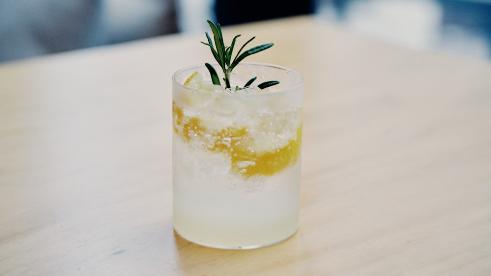 clear drinking glass with white liquid and green leaf