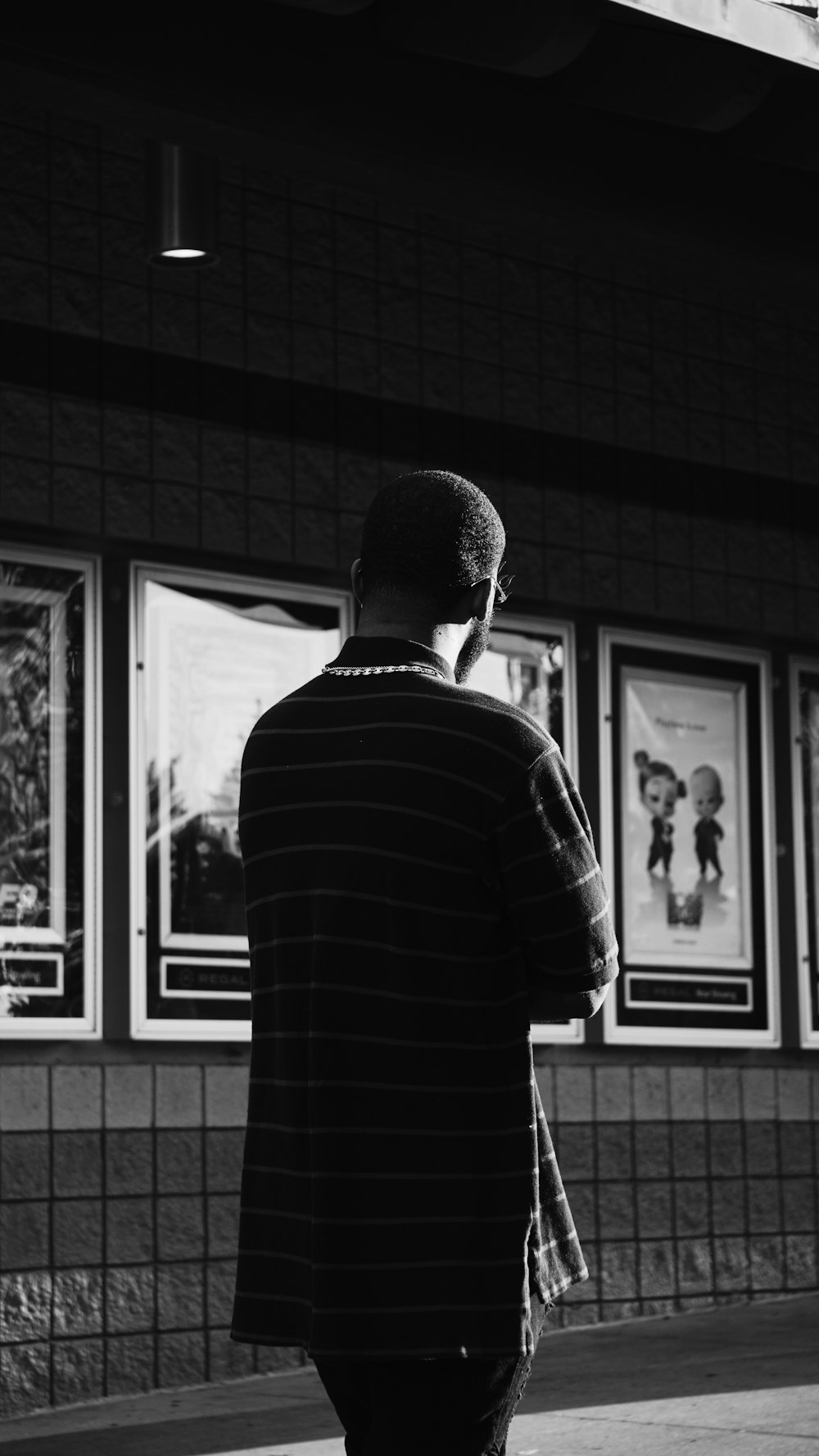 man in black and white striped long sleeve shirt standing in front of window