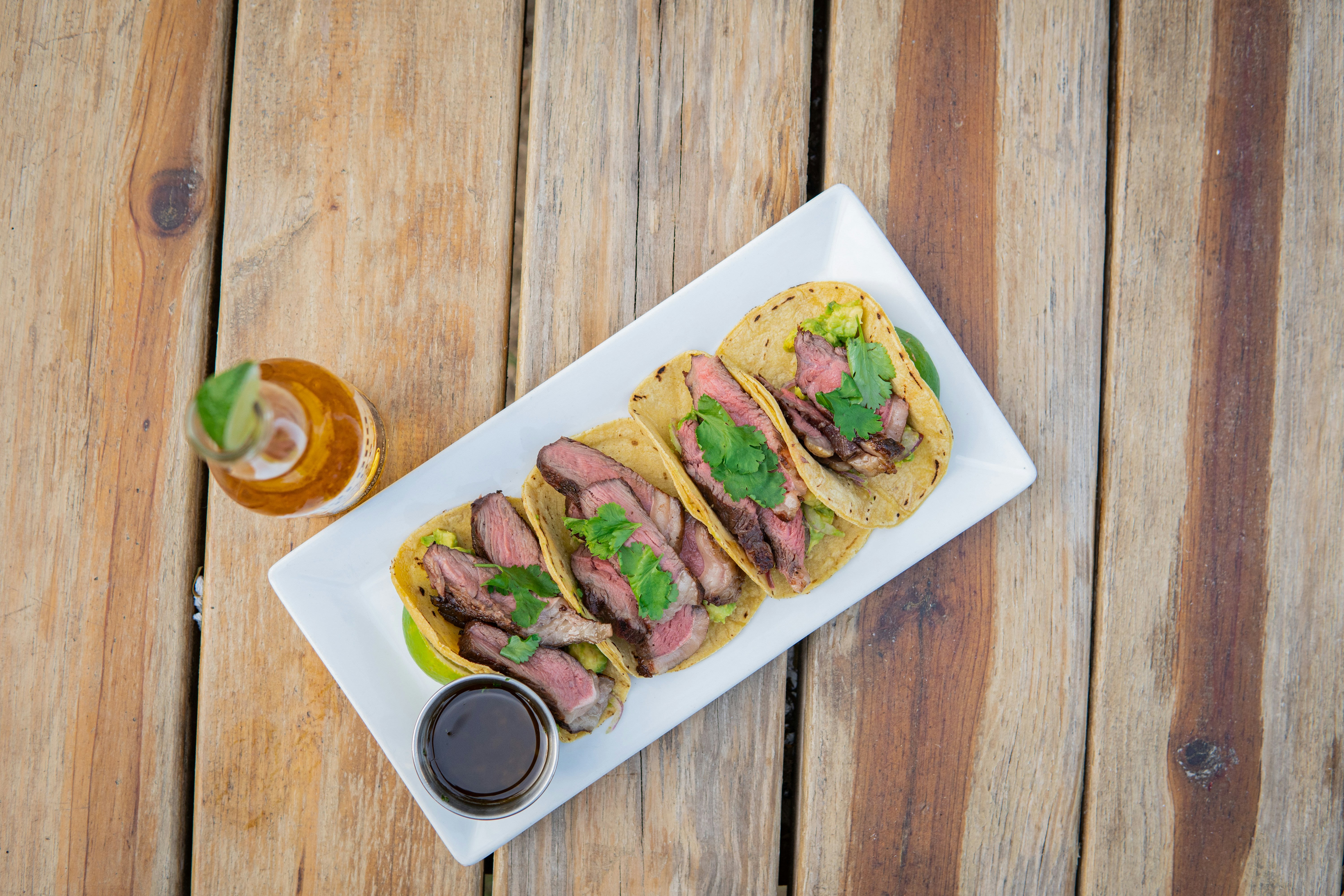 Steak tacos on a white tray over timber boards