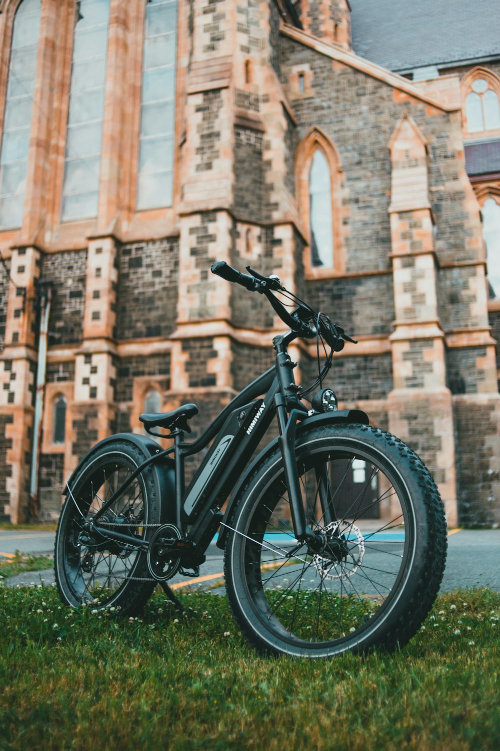 black bicycle parked beside brown brick wall