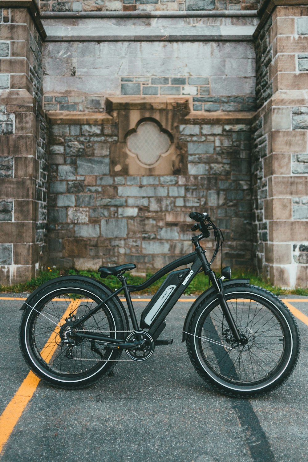 black and gray bicycle leaning on brown brick wall