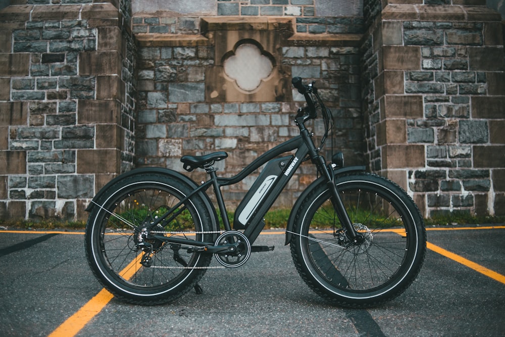 black and gray mountain bike leaning on brown brick wall
