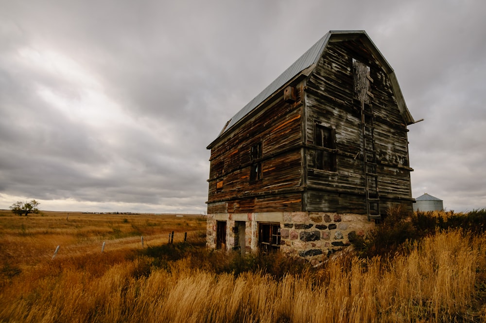 casa de madera marrón en un campo de hierba marrón bajo un cielo nublado gris
