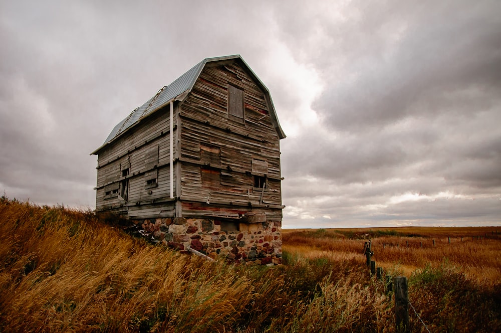 casa de madera marrón en campo de hierba verde bajo cielo nublado gris durante el día