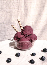 Bright strawberry ice cream swirled with fresh berry chunks in a bowl.