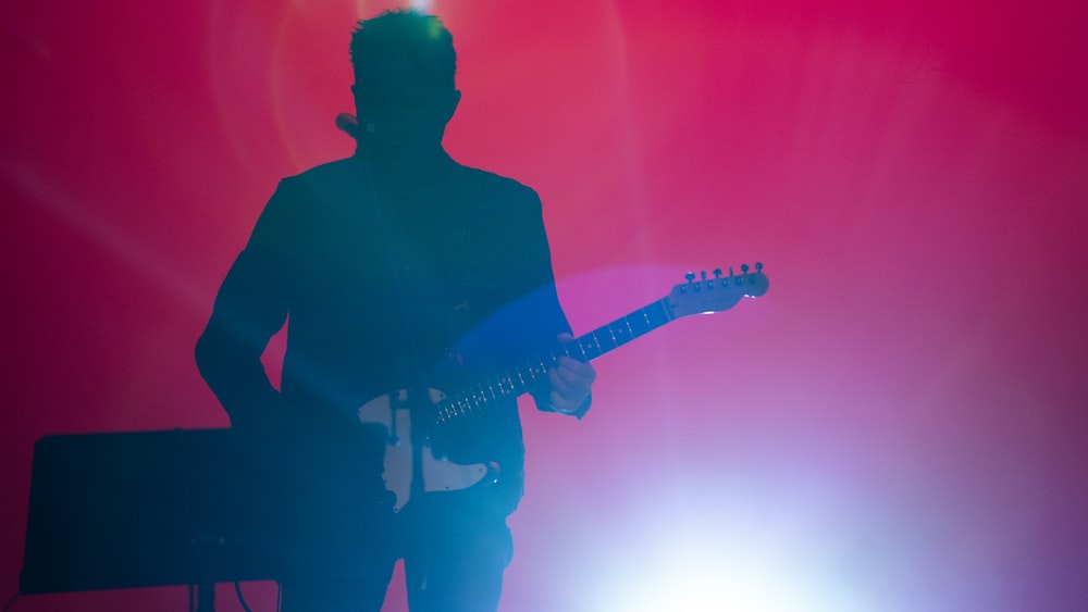 silhouette of man playing electric guitar