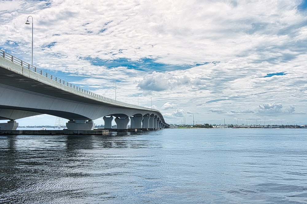 white bridge over the sea under white clouds and blue sky during daytime