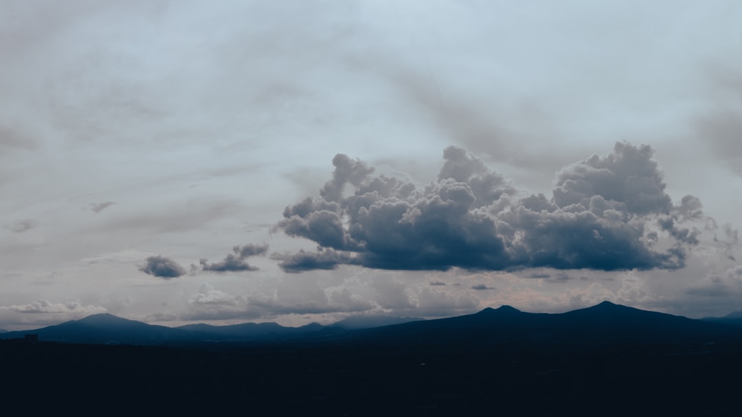 white clouds over silhouette of mountain