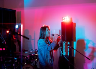 woman in blue denim jacket singing on stage