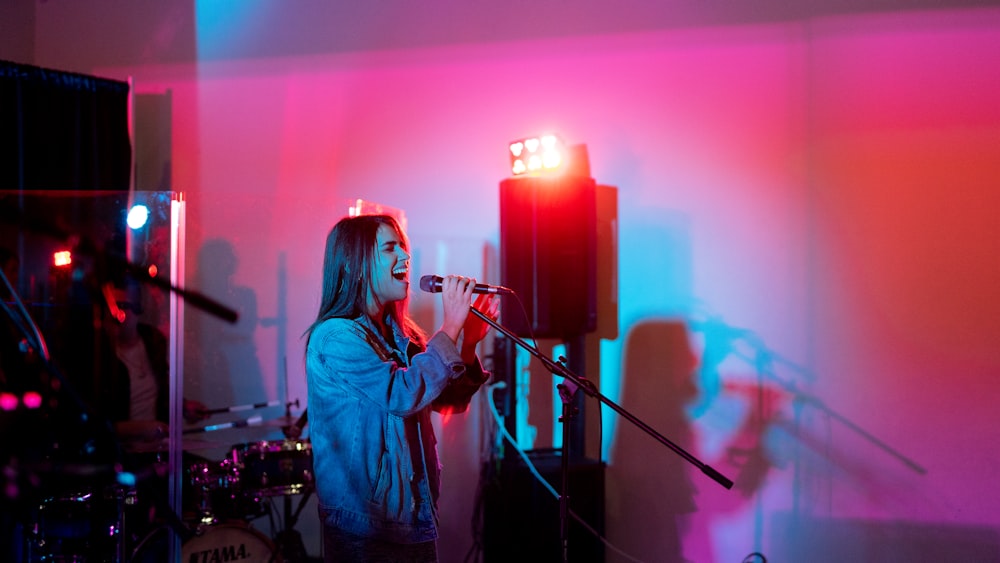 woman in blue denim jacket singing on stage