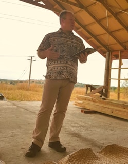A vibrant community health worker using a tablet to explain a health story to local villagers under a tree.