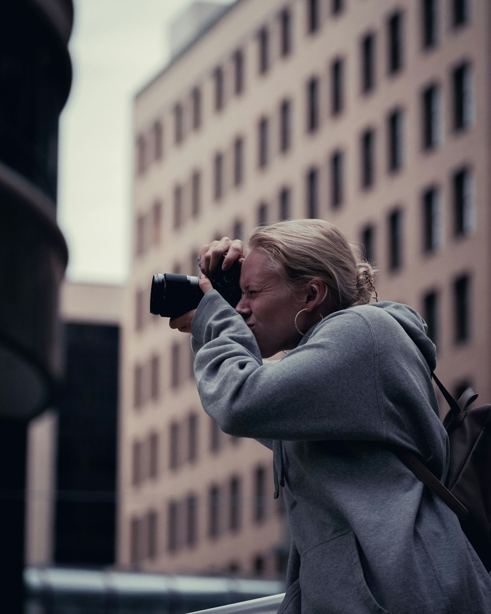 woman in gray hoodie holding black dslr camera