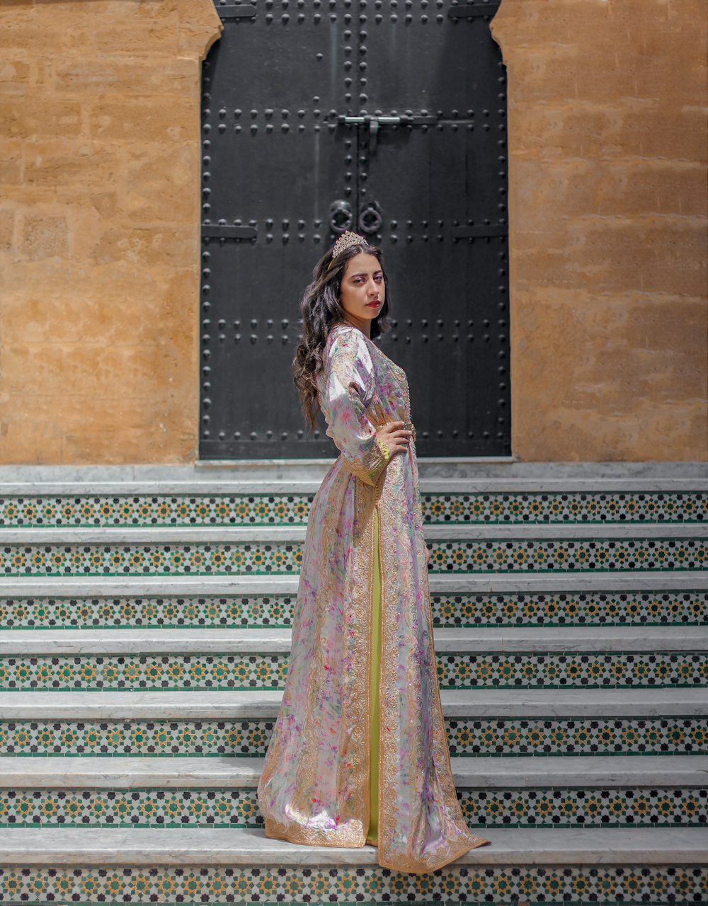 Femme en robe fleurie jaune et verte debout sur les escaliers