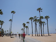 Tourists enjoying a scooter ride along the palm-lined Golden Beach under a clear blue sky.