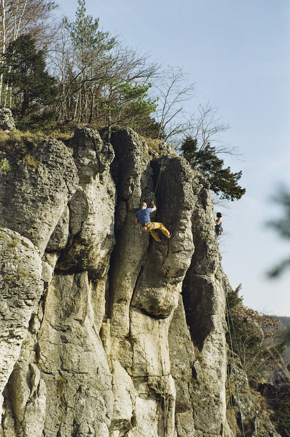 Hombre en chaqueta amarilla escalando en la montaña rocosa durante el día