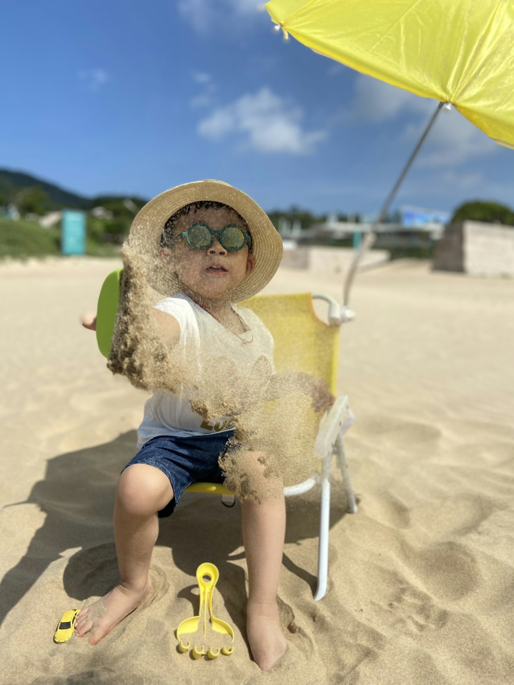 Mädchen in weißem Kleid sitzt tagsüber auf weißem Stuhl am Strand