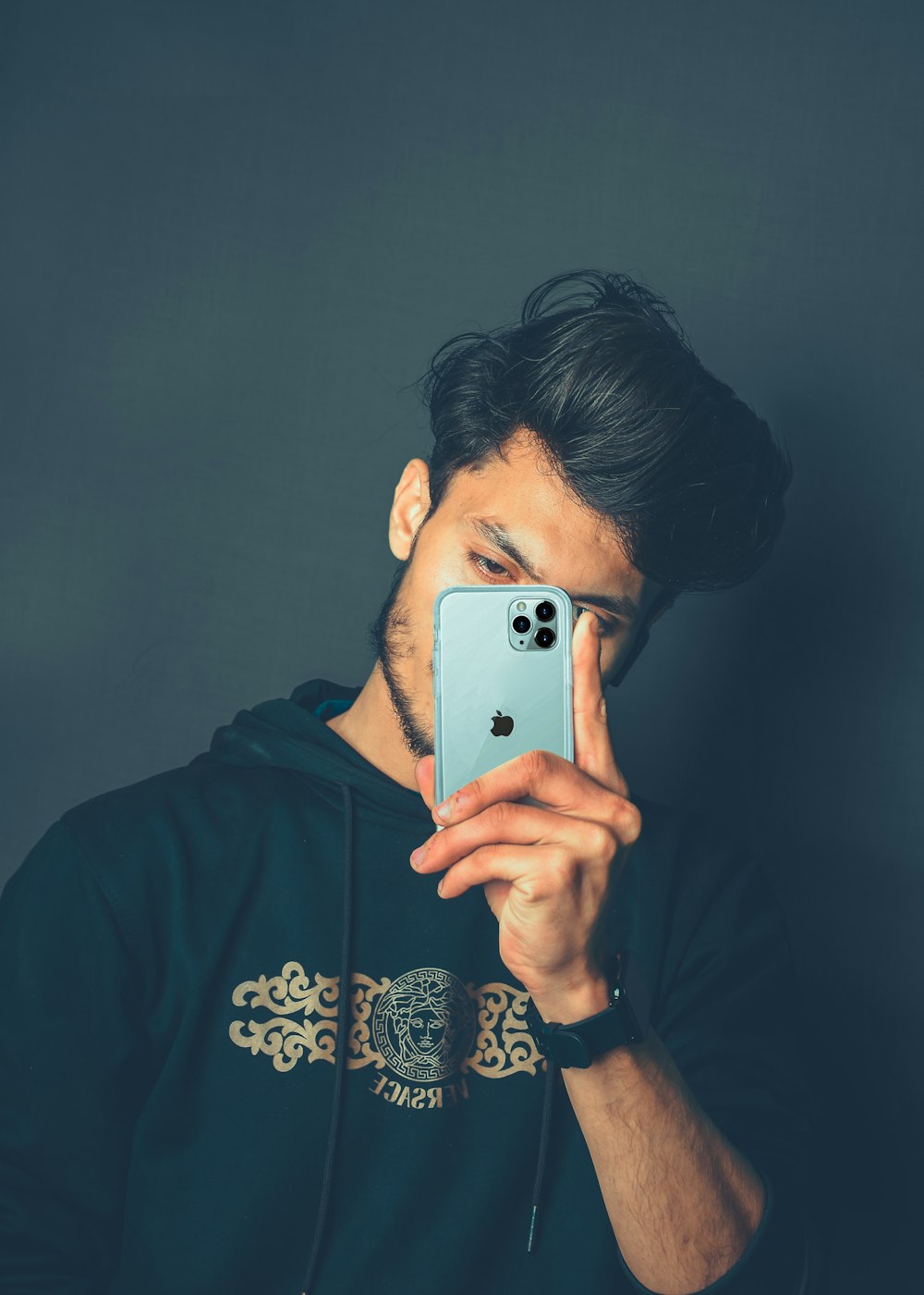 man in black hoodie holding silver iphone 6