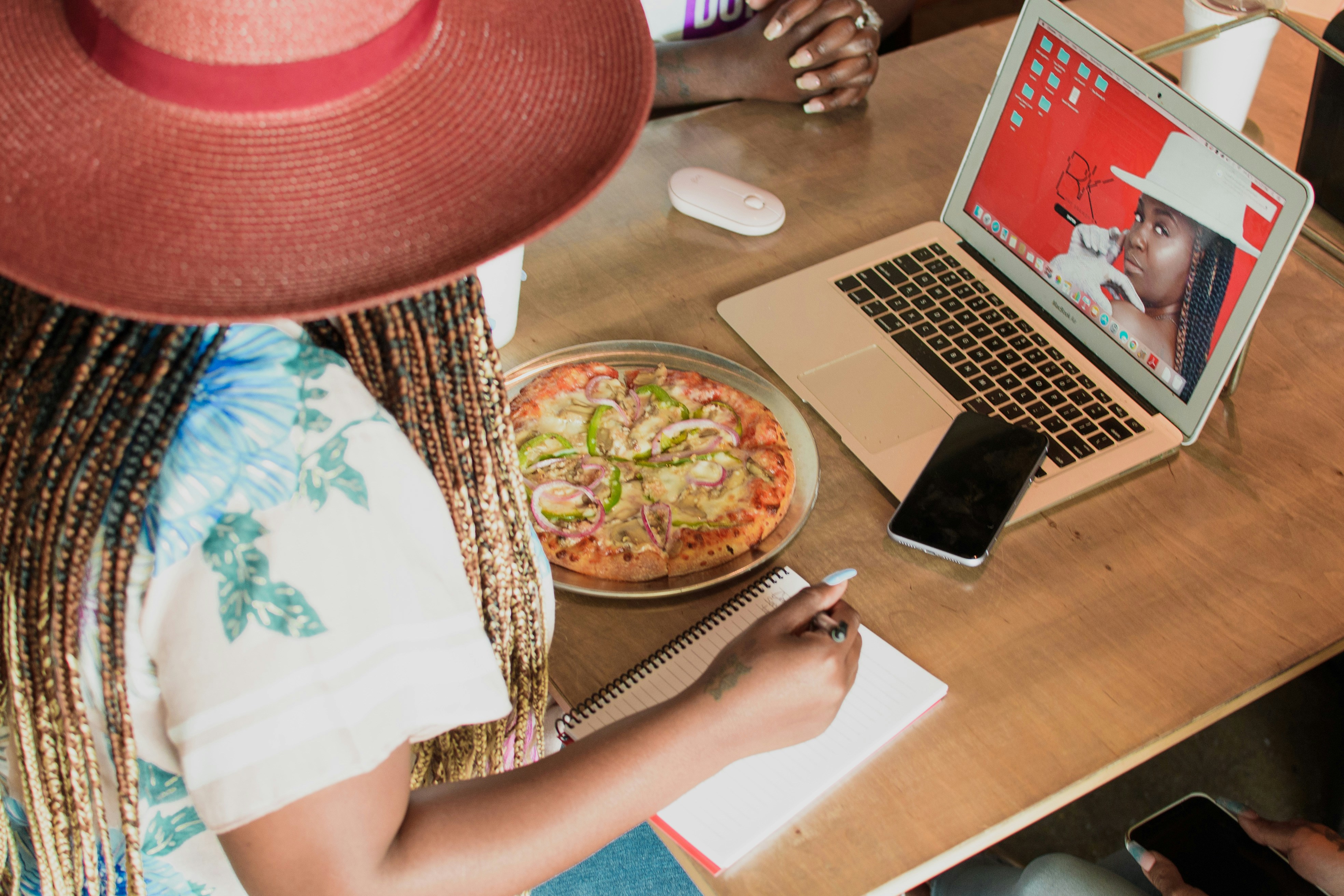 Wanita berbaju putih duduk di samping meja dengan MacBook Pro