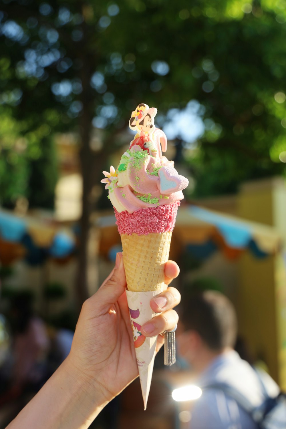 person holding ice cream cone with pink ice cream