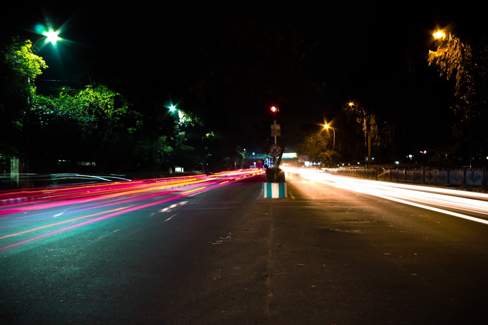 man in red jacket standing on road during night time