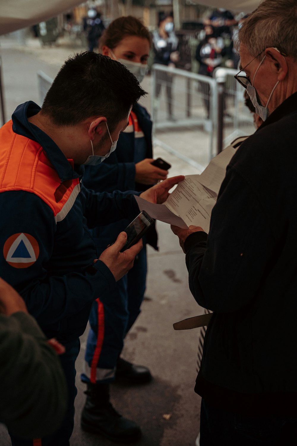 man in orange and black jacket holding white paper