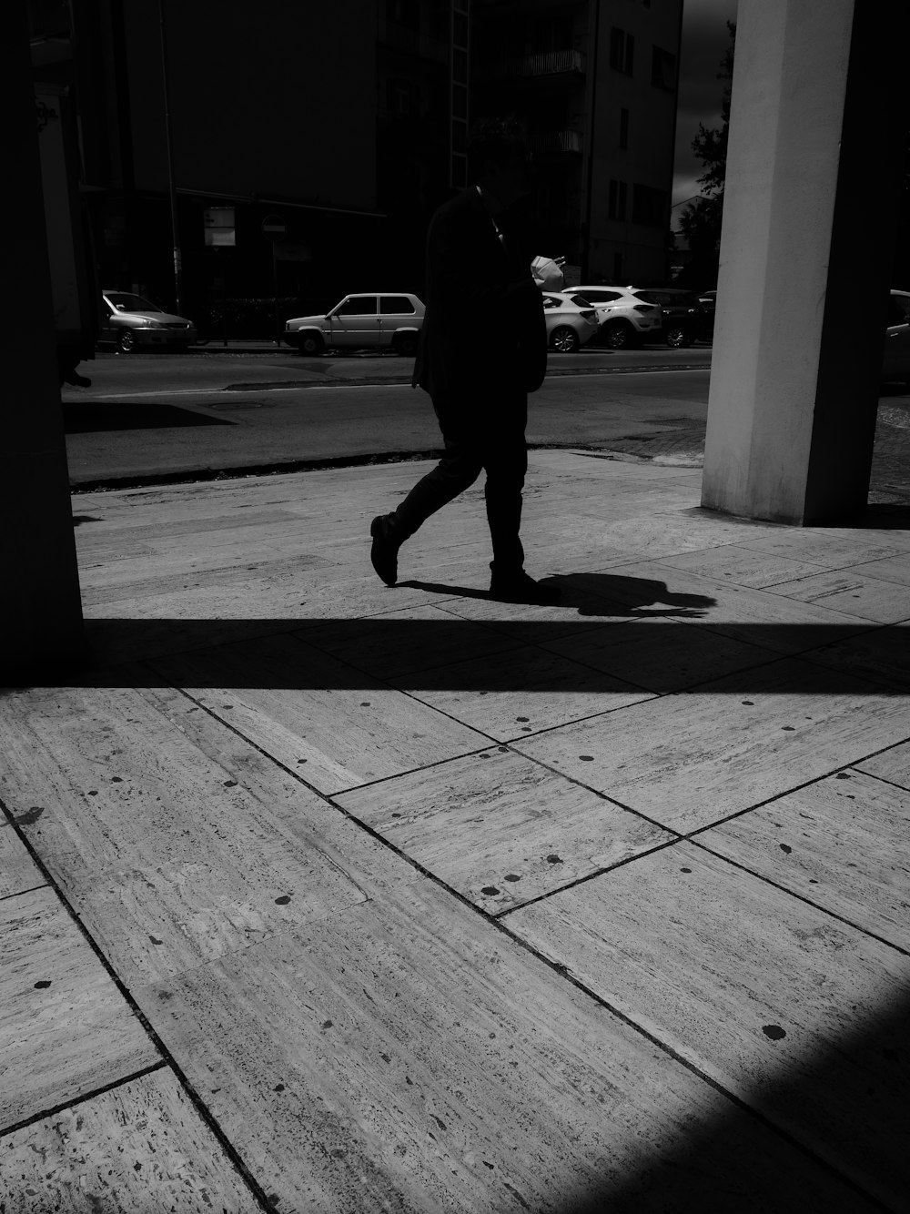 man in black jacket walking on sidewalk