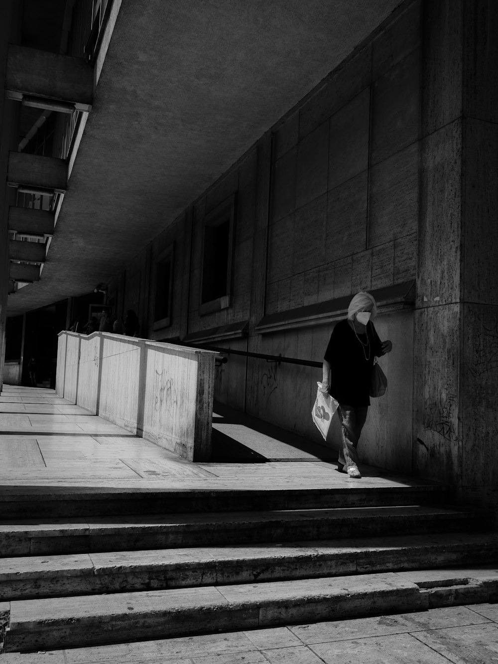 grayscale photo of woman in black long sleeve shirt and pants walking on hallway