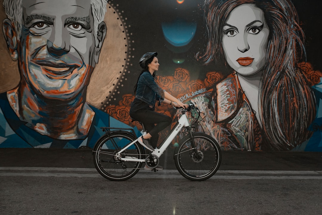 man in black jacket riding on blue bicycle