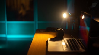 A dimly lit workspace with vintage film grain texture and a laptop open on a dark wooden desk.