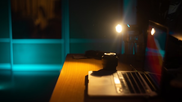 A dimly lit workspace with vintage film grain texture and a laptop open on a dark wooden desk.