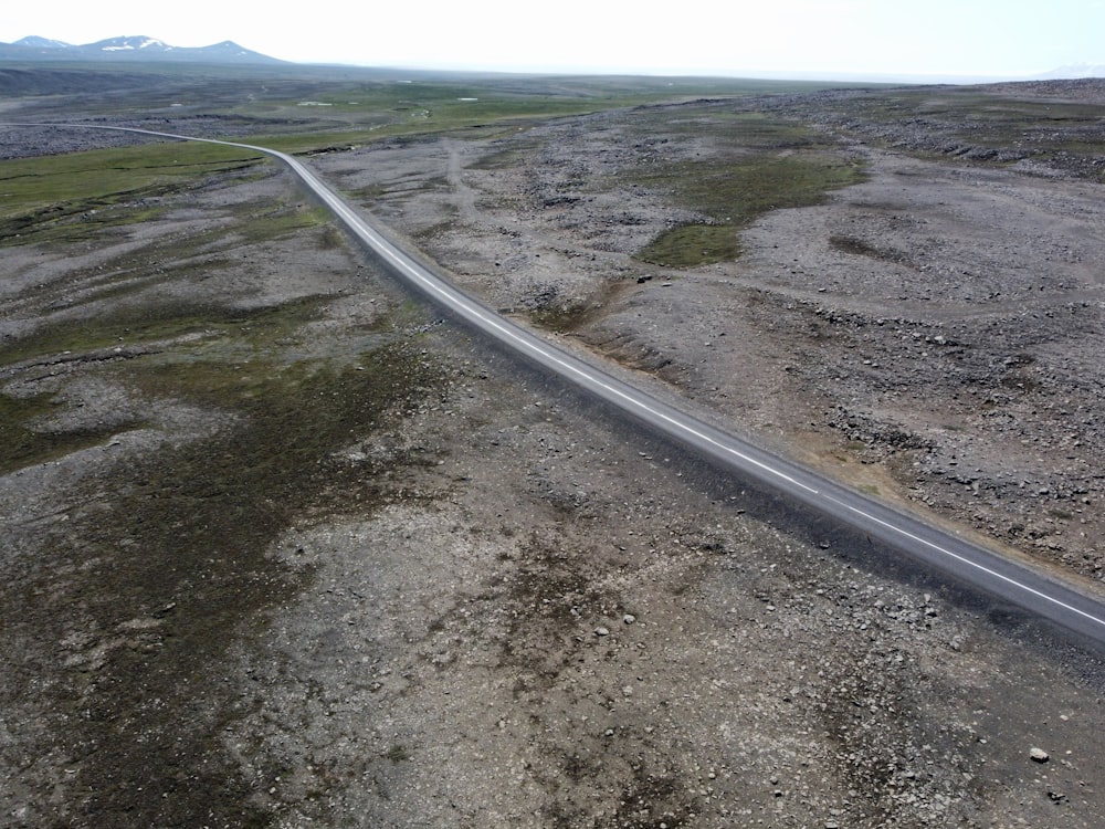 estrada de asfalto cinza entre campo de grama verde sob céu nublado branco durante o dia