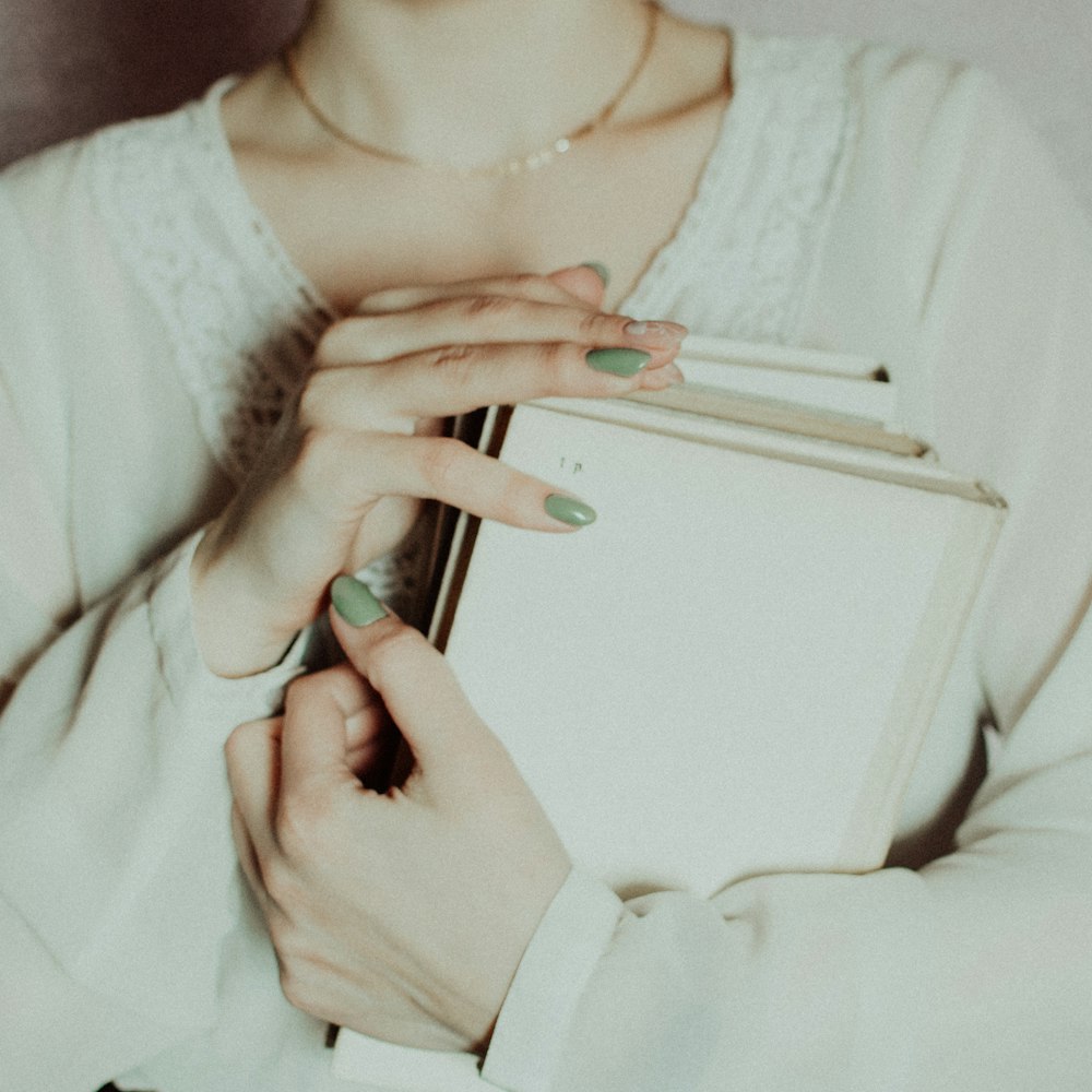 woman in white long sleeve shirt holding white smartphone