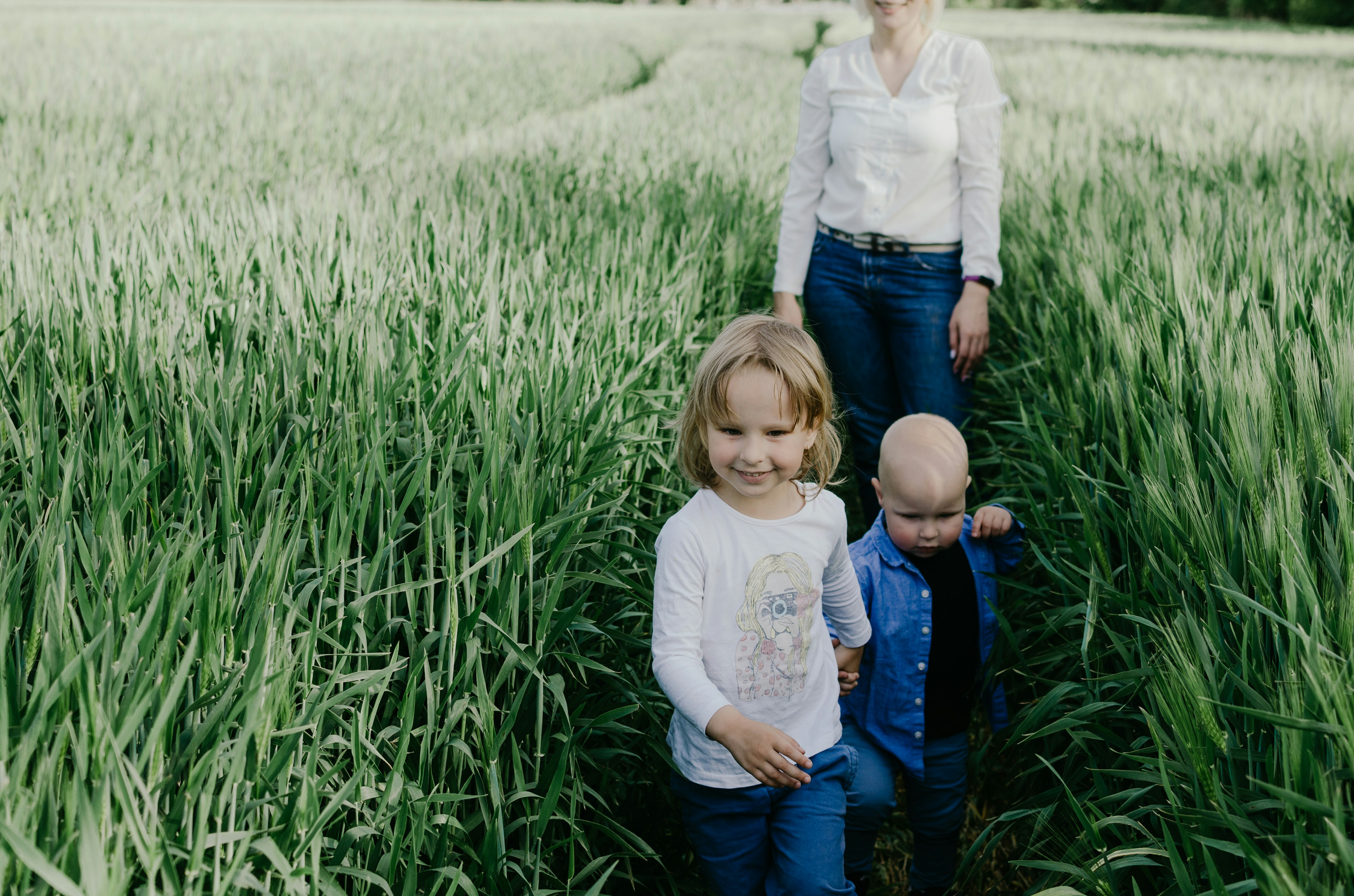 girl in white long sleeve shirt and blue denim jeans sitting on green grass field during
