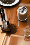 Elegant coffee accessories including a tamper and a milk frother on a wooden table