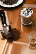 Elegant coffee accessories including a tamper and a milk frother on a wooden table