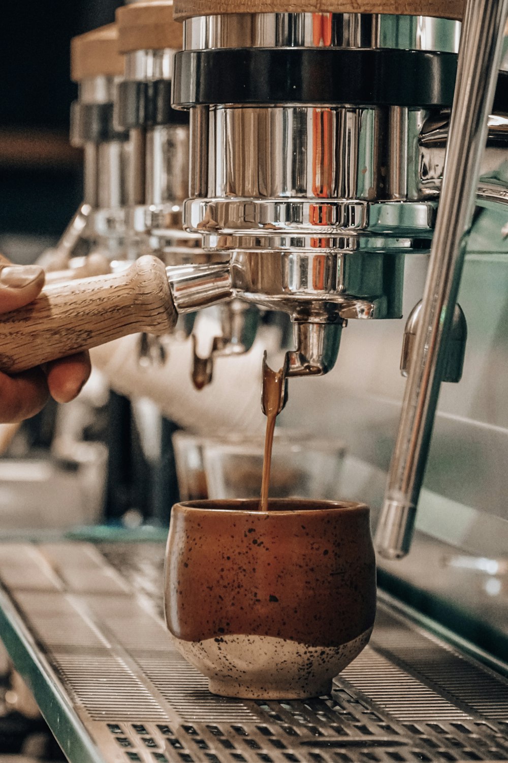 透明なコップに茶色の液体を注ぐ人